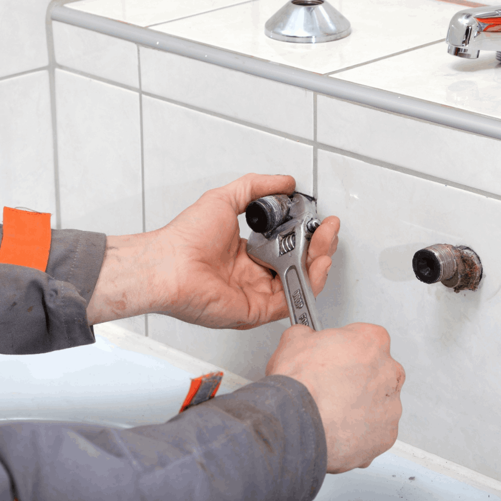 Plumber with a wrench in his hand repairs the faucet