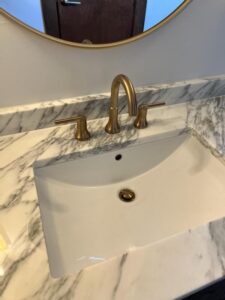 a bathroom sink with gold faucet and mirror