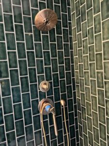 a green tiled shower with a shower head and shower head
