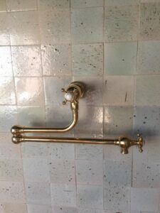 a brass shower handle on a tiled wall
