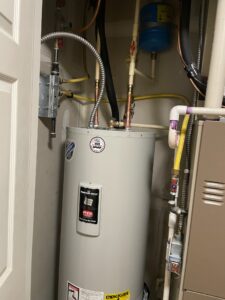 a water heater in a room with pipes and a door
