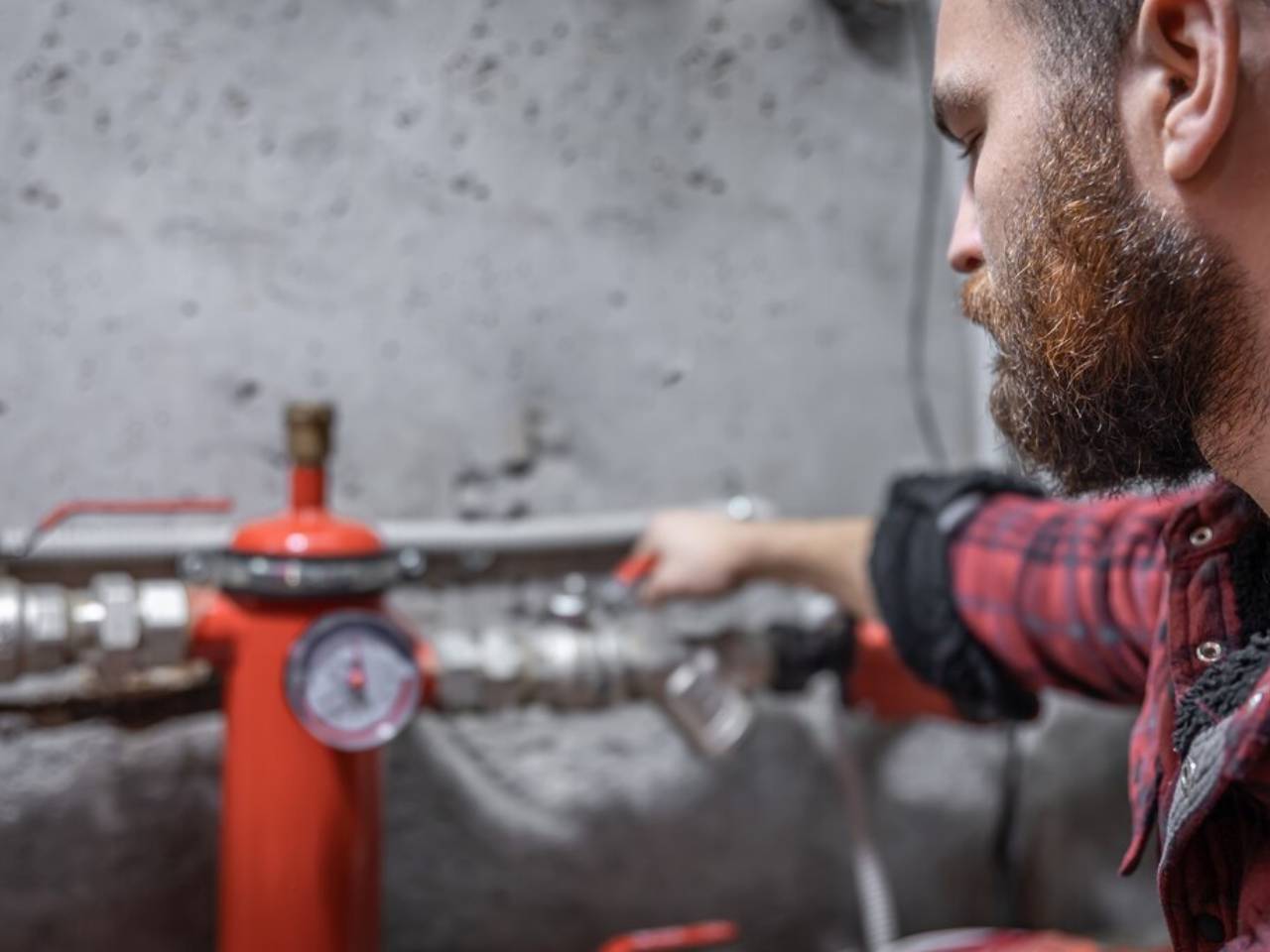 man looks at the faucet, pipes, valve, pressure meter.