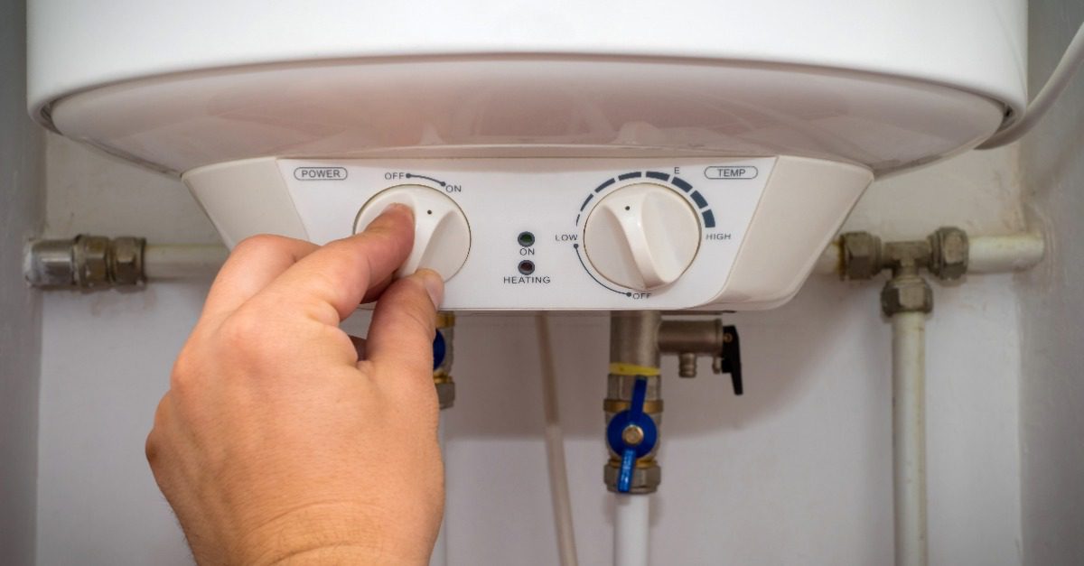 Close-up of male hands adjusting the temperature of the gas boiler