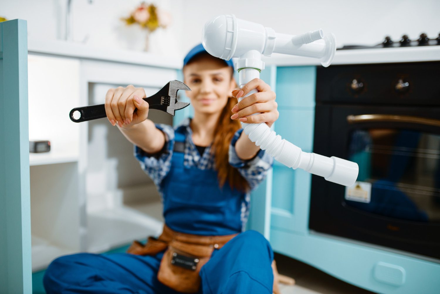 young-female-plumber-uniform-shows-wrench-pipe-kitchen-handywoman-with-toolbag-repair-sink-sanitary-equipment-service-home